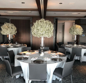 Reception tables with white tablecloths and tall arrangements of baby's breath on clear stands