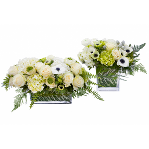 Two Flower arrangements,  Tetra : Flower arrangement in a low, square, clear glass vase, green hydrangea, white hydrangea, white roses, white anemones, white ranunculus, leather leaves and silver pinecones Grand Tetra : Flower arrangement in a low, rectangle, clear glass vase, white and green hydrangea, white hydrangea, white roses, white anemones and white ranunculus