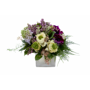 Flower arrangement in a low, square, white, ceramic vase, lilac, lavender hyacinths, purples anemones, white ranunculus, seeded eucalyptus and asparagus fern.