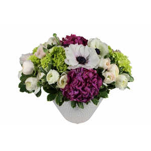 Flower arrangement in a medium tall, oval, white ceramic vase, purple hydrangea, green hydrangea, white ranunculus and white anemones