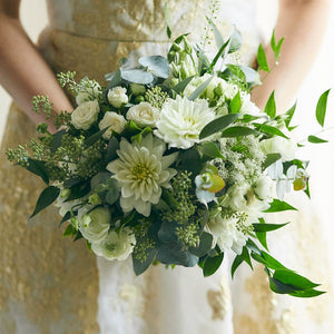 Bride holding a wedding bouquet of white flowers and lush greenery
