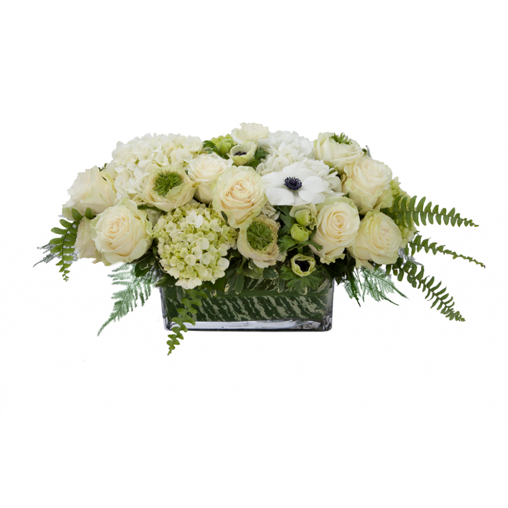 Flower arrangement in a low, rectangle, clear glass vase, white and green hydrangea, white hydrangea, white roses, white anemones and white ranunculus