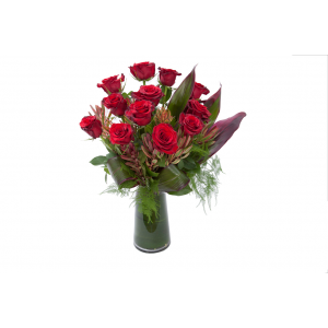 Flower arrangement in a tall, round, clear glass vase, red roses, red safari sunset and red aspidistra leaves