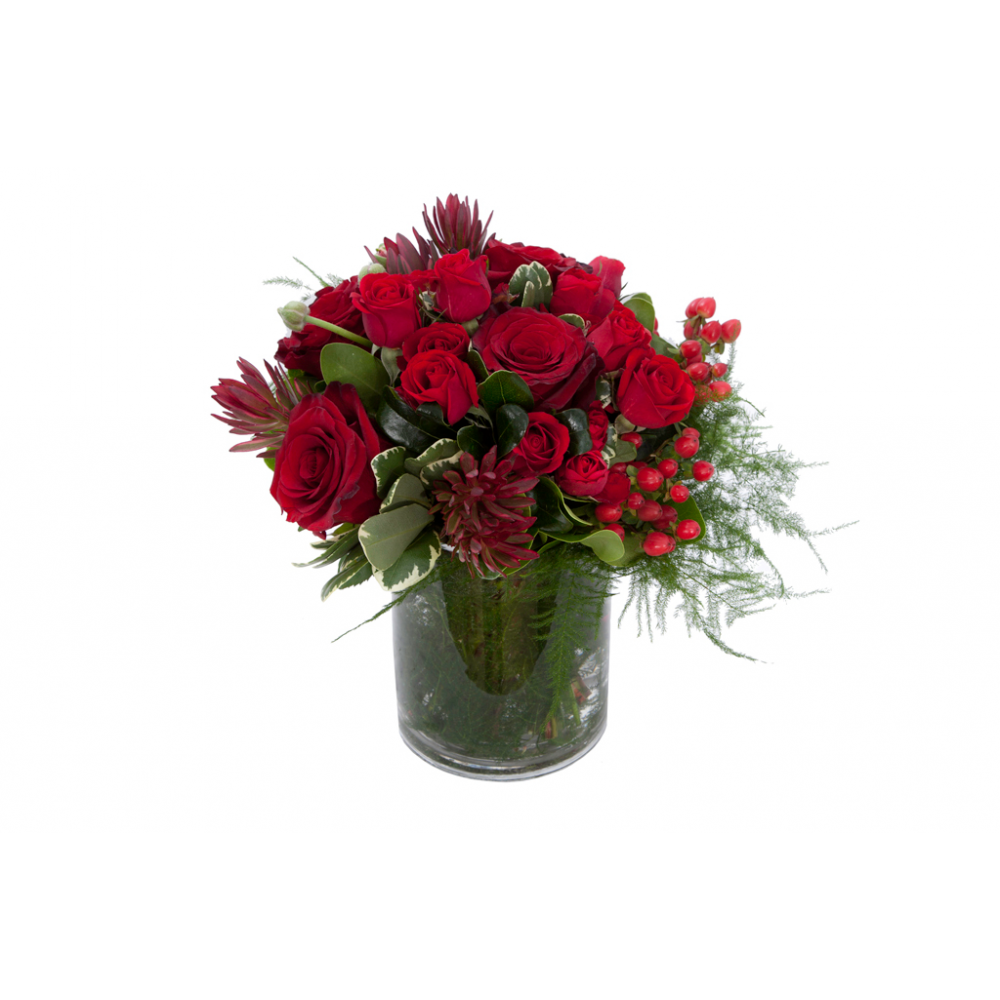 Flower arrangement in a low, round, clear vase, red roses, red spray roses, red hypericum, safari sunset