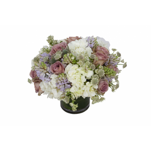 Flower arrangement in a low, round, clear glass vase, white hydrangea, pink roses, lavender hyacinths and white astrantia