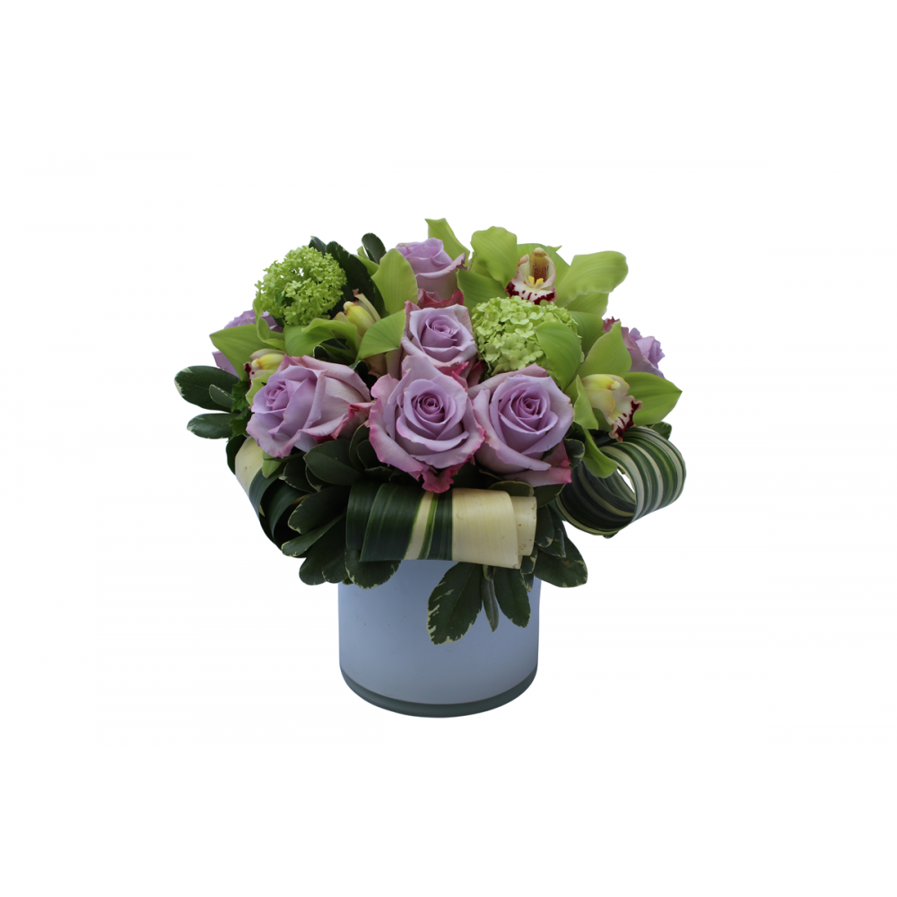Flower arrangement in a low, round, white glass vase, lavender roses, green viburnum, green cymbidium orchids and folded aspidistra leaves