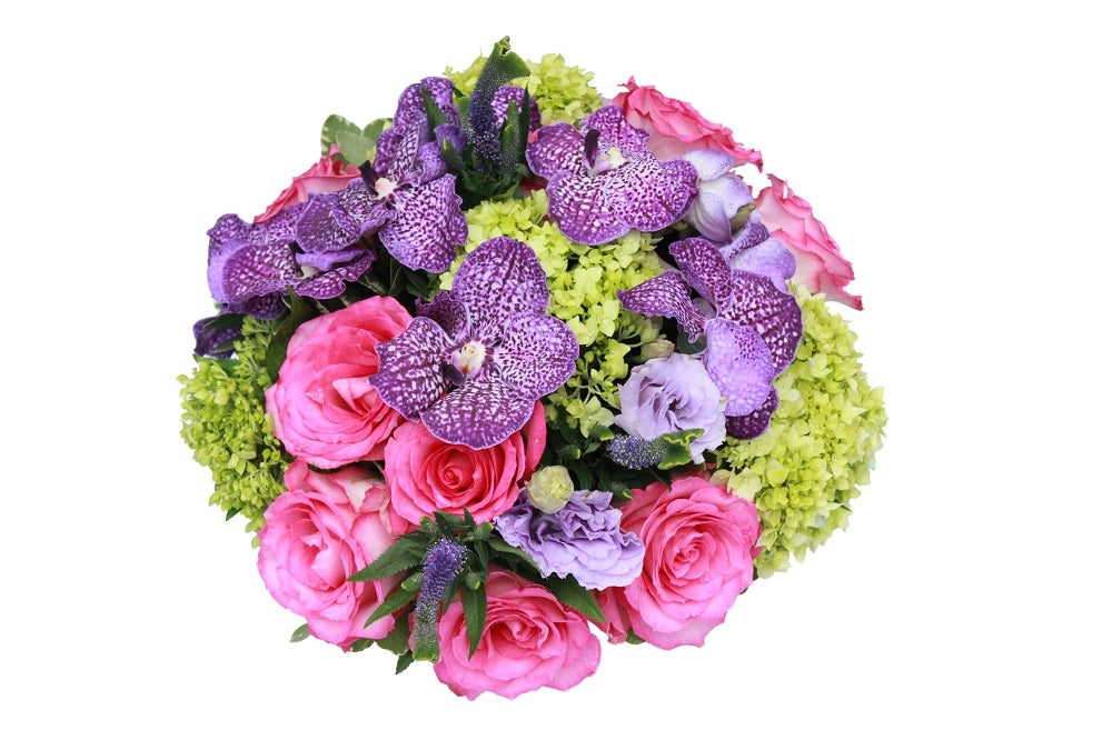 Flower arrangement in a low, round, black, ceramic vase, pink roses, purple vanda orchids, green hydrangeas and blue veronicas