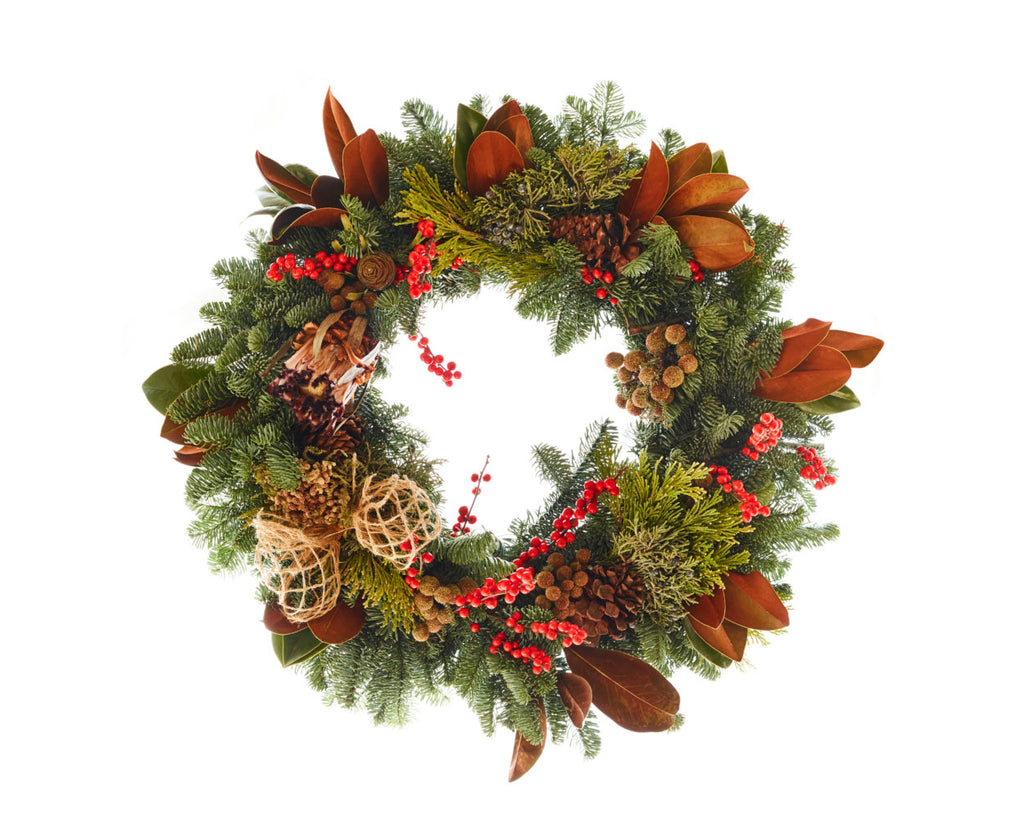 Pine wreath with magnolia leaves, pine cones, red berries and a raffia bow