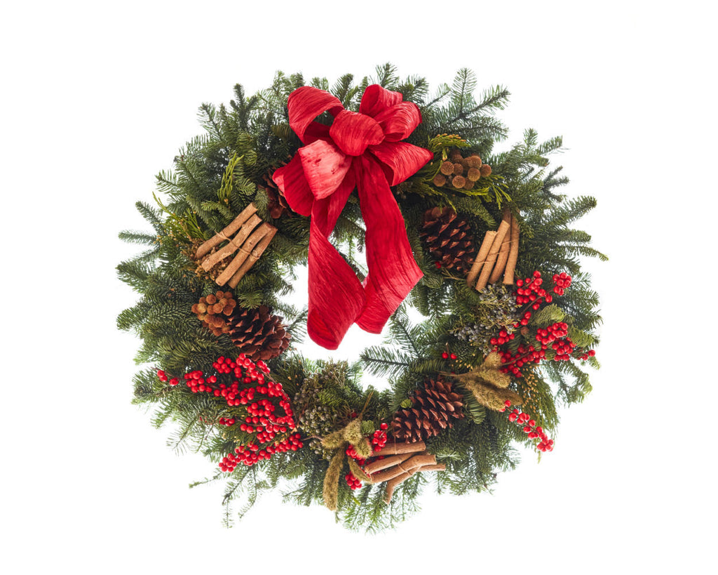 Pine wreath with cinnamon stick, pine cones, red berries and a red bow