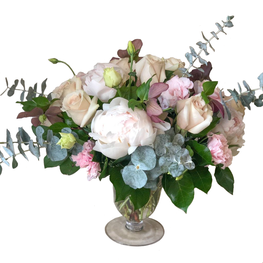 Flower arrangement in a low, tulip shape, glass vase, white peonies, pink hellebores, pink roses, pink lisianthus and spiral eucalyptus