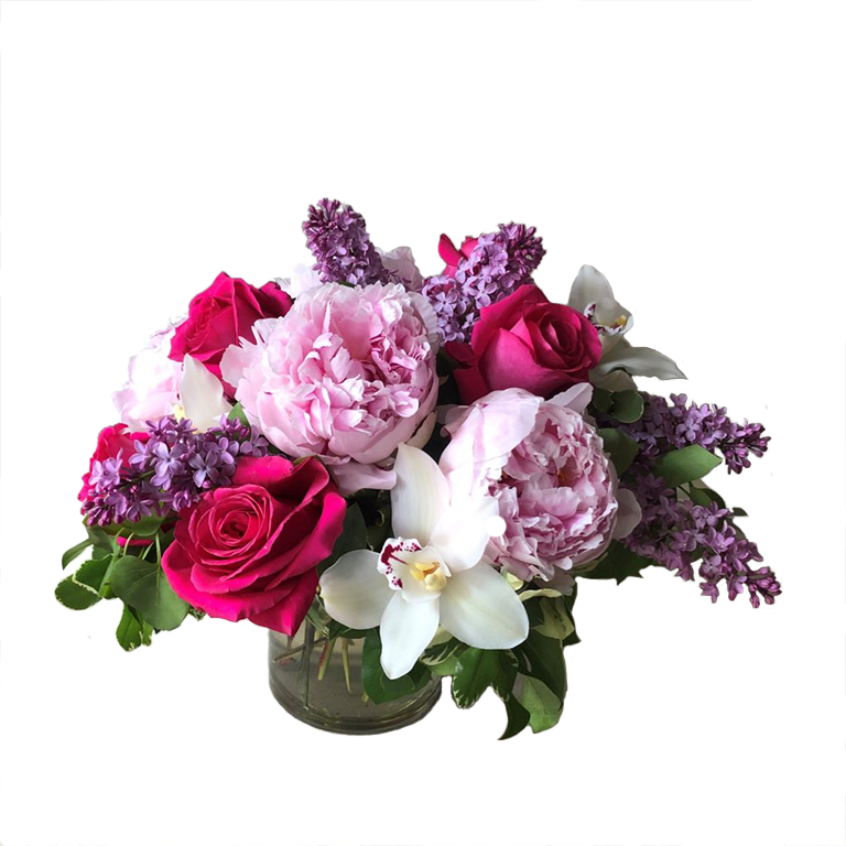 Flower arrangement in a low, round, clear glass vase, pink roses, pink peonies, lilac and white cymbidium orchids